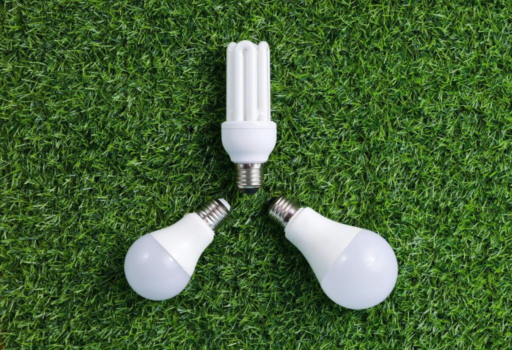 Különböző típusú E27 és GU10 LED izzók zöld füvön elhelyezve, a TEMA környezetbarát világítástechnikai megoldásait szemléltetve.