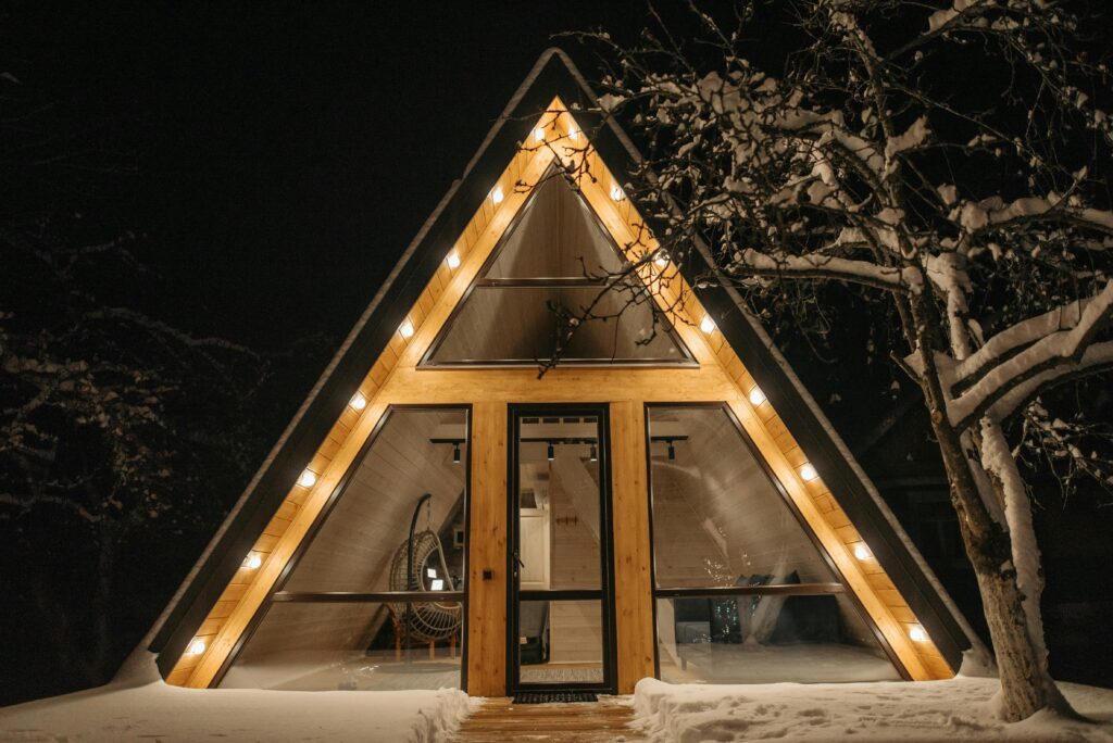 Modern design tiny house éjszakai díszkivilágítással a havas téli tájban – professzionális épületvillamossági kivitelezés a TEMA-tól.